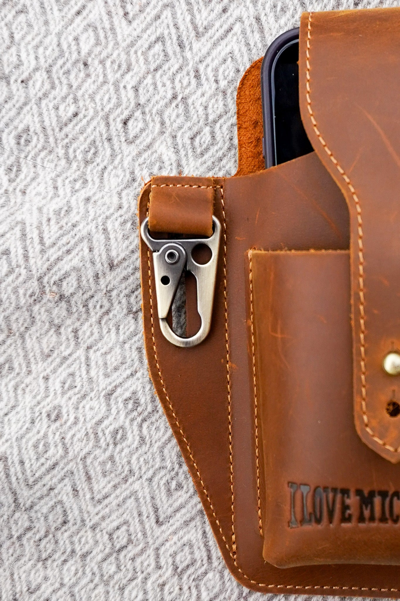 Brown leather phone case with a clip on a textured gray background